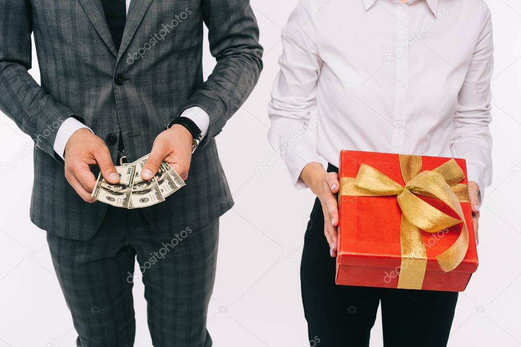 cropped image of businesspeople holding dollars and gift box isolated on white