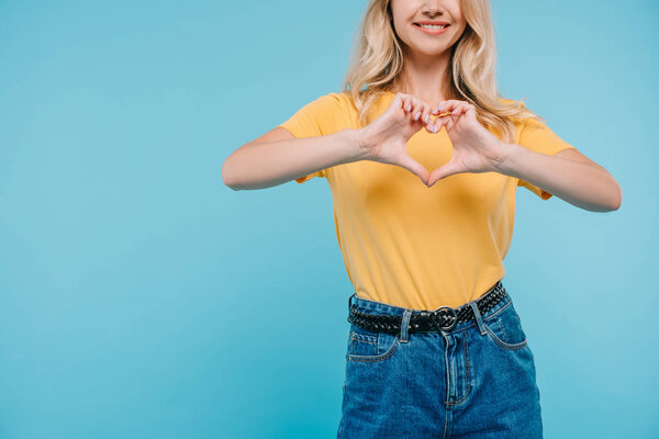 обрезанный образ девушки в рубашке и шортах, показывающих сердце с руки изолированы на синий
