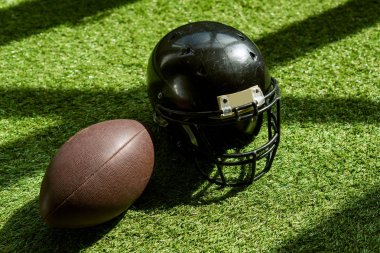 yeşil çimenlerin üzerinde Amerikan futbolu topu ve kask yüksek açılı görünüş
