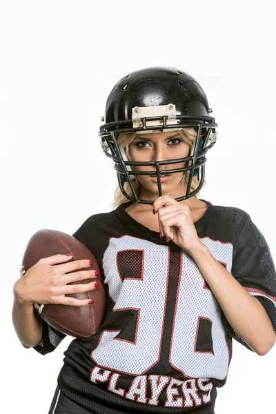 serious young woman in american football uniform with ball looking at camera isolated on white