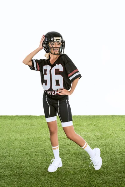 立っているアメリカン フットボール制服白で隔離緑の草の上に魅力的な若い女性  — 無料ストックフォト