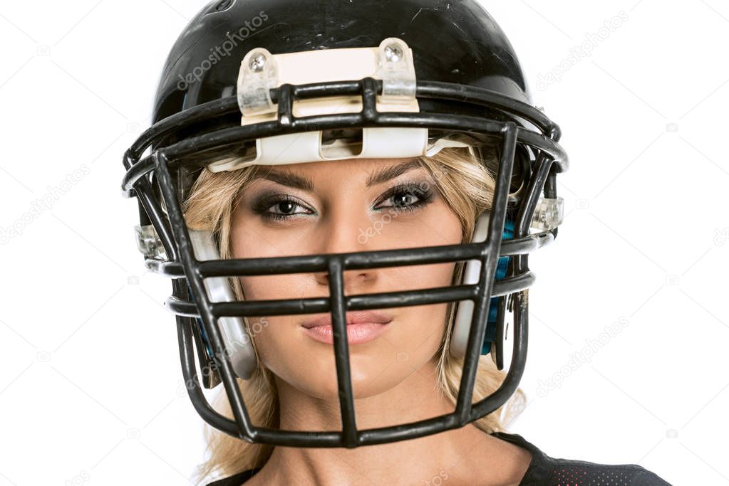 close-up shot of serious young woman in american football helmet looking at camera isolated on white