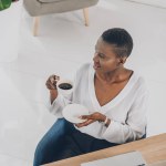 Vysoký úhel pohled stylové atraktivní africká americká podnikatelka držící šálek kávy v kanceláři