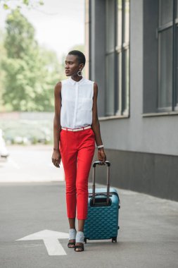 moda çekici Afro-Amerikan işkadını seyahat çantası ile sokakta yürürken