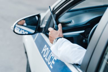 cropped image of male police officer holding radio set in car  clipart