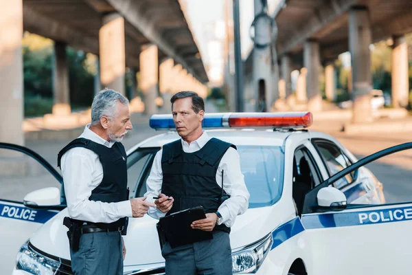 Middle Aged Policeman Talking Colleague Clipboard Car Street — Stock Photo, Image