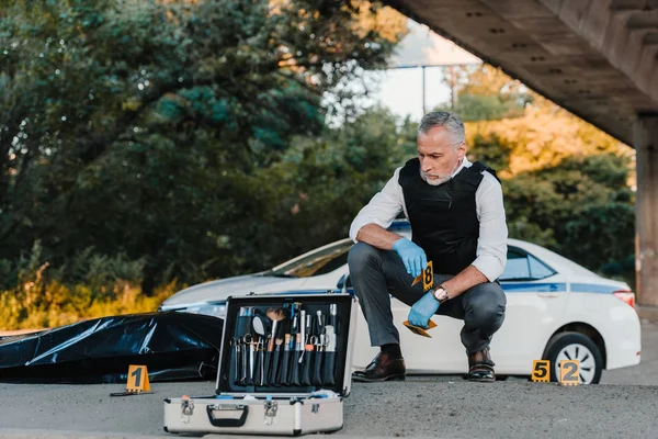 Polizist Mittleren Alters Latexhandschuhen Sitzt Tatort Mit Leiche Leichensack — Stockfoto