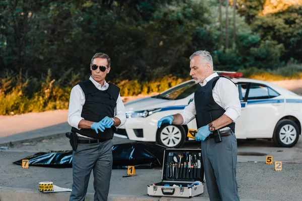 Mature Policeman Latex Gloves Pointing Finger Colleague Sunglasses Standing Crime — Free Stock Photo