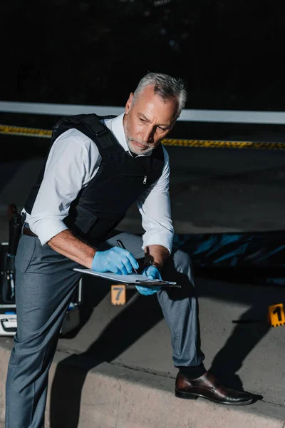 Serious Middle Aged Policeman Writing Clipboard Crime Scene Corpse Body — Free Stock Photo