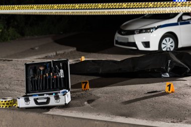araştırma araçları, Araba, polis hattı ve olay yerindeki ceset torbası içinde ceset ile durum 