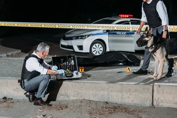 Policial Sexo Masculino Sentado Perto Caso Para Ferramentas Investigação Enquanto — Fotografia de Stock