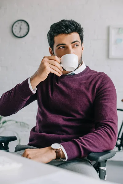 オフィスでコーヒーを飲みながらブルゴーニュのセーターでハンサムなデザイナー  — 無料ストックフォト