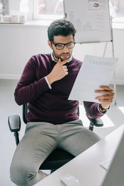Pensive Handsome Designer Burgundy Sweater Sitting Chair Reading Documents Office — Free Stock Photo