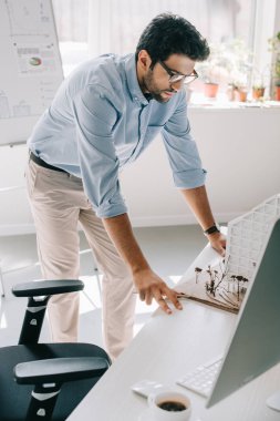masanın üzerine eğilerek ve mimari modeli Office bakarak yakışıklı mimar