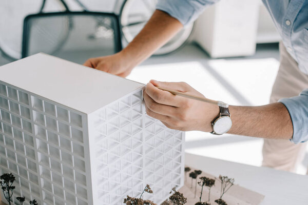 cropped image of architect working with architecture model on table in office 