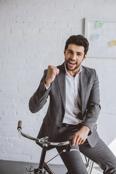 Feliz Hombre Negocios Guapo Sentado Bicicleta Mostrando Gesto Oficina — Foto de Stock