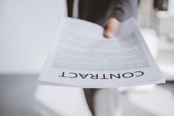 cropped image of businessman showing contract in office