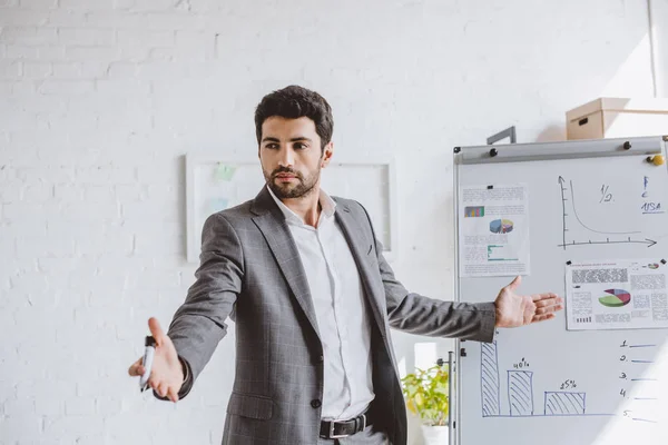 Schöner Geschäftsmann Präsentiert Projekt Auf Flipchart Und Gestikuliert Büro — Stockfoto