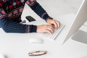 oříznutý pohled podnikatel vánoční svetr tisk na klávesnici v moderní kanceláři