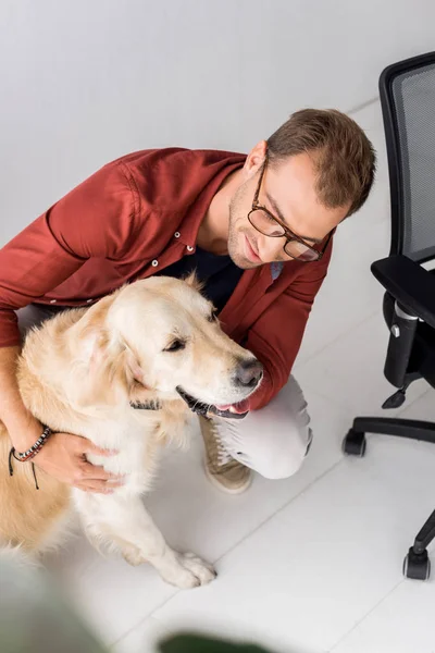 Человек Обнимает Золотую Собаку Ретривер Возле Стула — Бесплатное стоковое фото