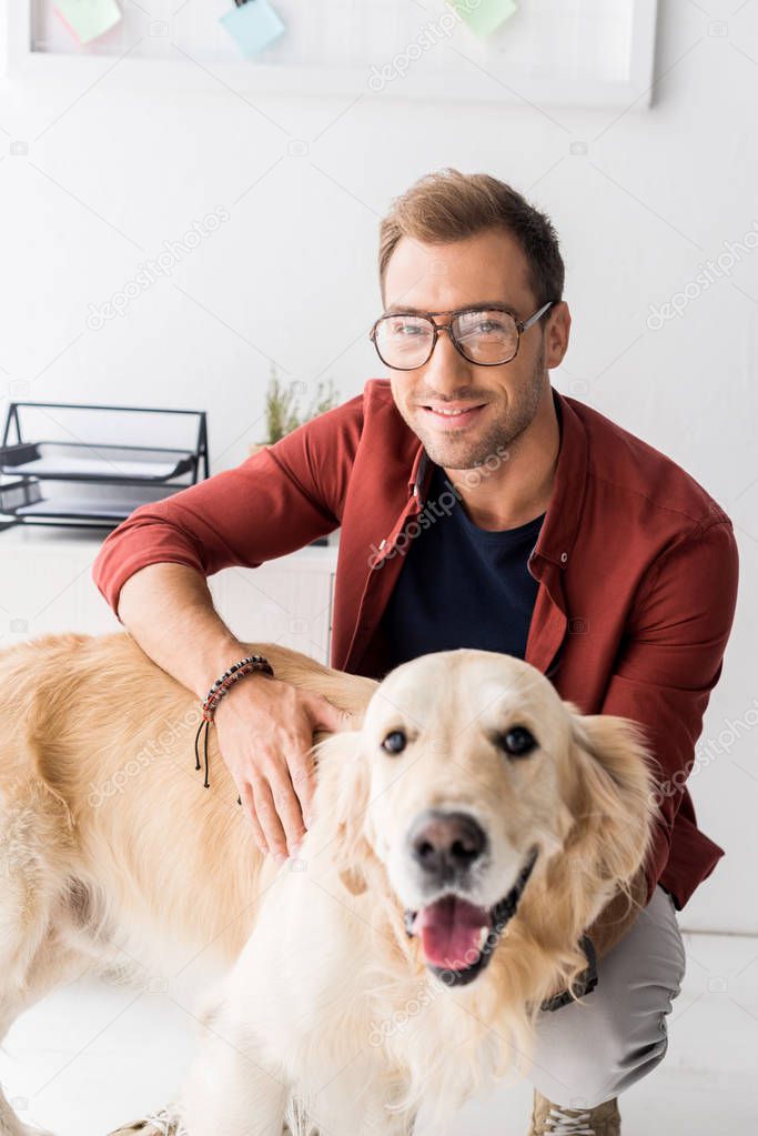 happy man in glasses stroking golden retriever dog