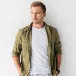 Casual man with hands in pockets against white wall