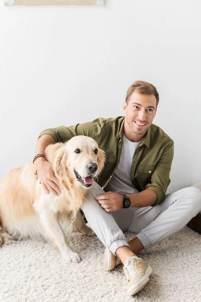 Uomo Cane Golden Retriever Seduto Sul Tappeto Beige — Foto stock gratuita