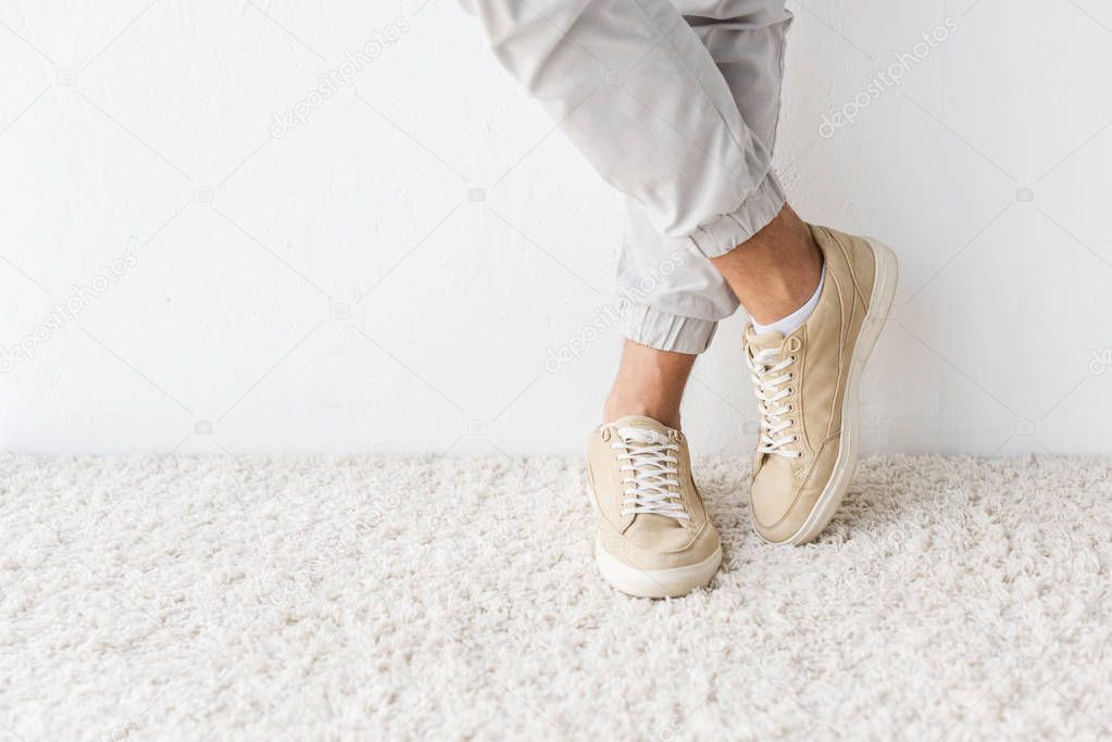 cropped view of casual man standing on beige rug 