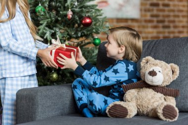Çocuk sunan Noel hediyesi sevimli gülümseyen kardeşim kadeh kırpılmış  