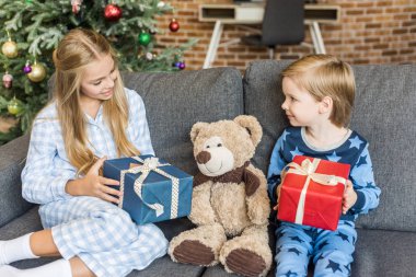 Noel hediyelerini tutarak ve oyuncak ayı seyir pijama mutlu çocuk
