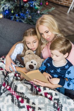 bir anne Noel zamanda şirin çocuk pijama ile kitap okuma yüksek açılı görünüş 