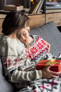 yüksek açı görüntülemek güzel genç çiftin birlikte kanepede oturan ve Noel hediyeleri tutarak