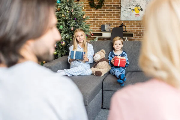 Selective Focus Parents Foreground Happy Kids Pajamas Holding Christmas Presents — Free Stock Photo