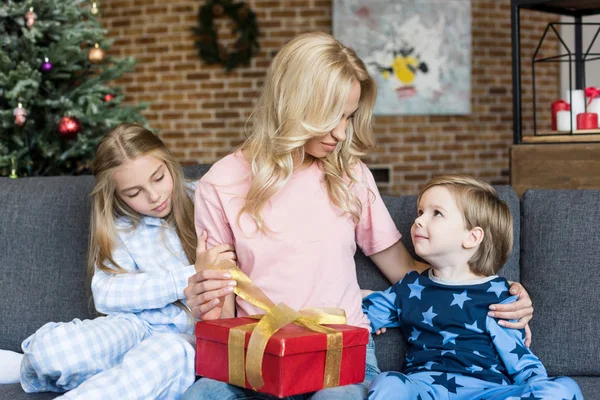 Jeune Mère Ouvrant Cadeau Noël Tout Étant Assis Avec Mignons — Photo gratuite