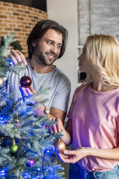 Happy Young Couple Decorating Christmas Tree Looking Each Other — Free Stock Photo