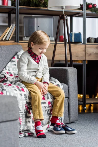 Urocza Szczęśliwe Dziecko Siedzi Kanapie Patrząc Buty — Darmowe zdjęcie stockowe