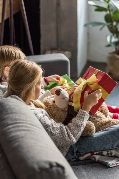 Vista Lateral Los Niños Sentados Sofá Apertura Regalos Navidad — Foto de stock gratis