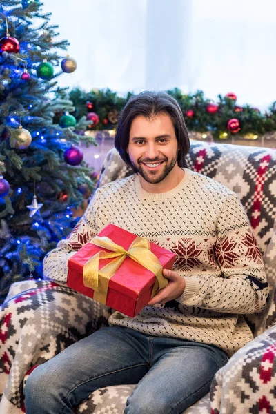Happy Young Man Holding Christmas Present Smiling Camera — Free Stock Photo