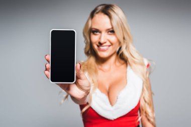 seçici odak Noel elbise gösteren smartphone ile boş ekran gri arka plan üzerinde izole içinde genç kadın
