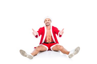 Noel Baba kostüm geniş kollu beyaz arka plan üzerinde izole katta oturan mutlu kaslı adam