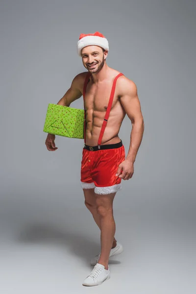 Lachende Gespierde Man Kerstmuts Shorts Houden Doos Van Gift Geïsoleerd — Gratis stockfoto