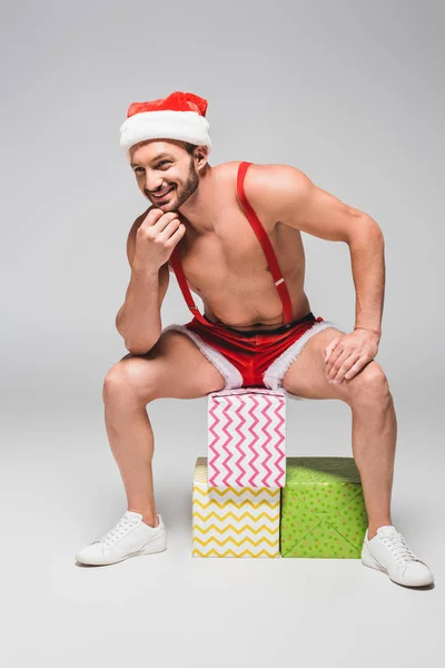 Homme Musclé Souriant Chapeau Short Noël Assis Sur Des Boîtes — Photo gratuite