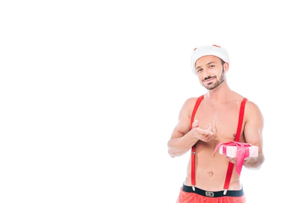快乐的无上衣肌肉男子在圣诞帽指向在白色背景上孤立的礼品盒 — 免费的图库照片