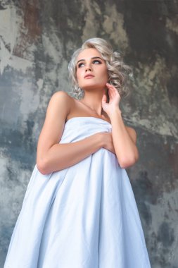 Alt görünümü çekici çıplak genç kadının vücudu grungy beton duvar önünde beyaz bezle kapsayan