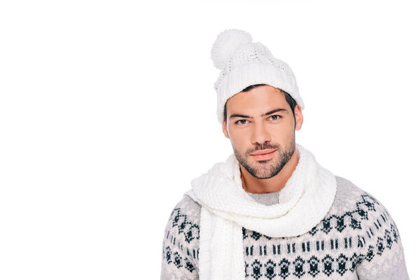 portrait of handsome young man in sweater, scarf and hat looking at camera isolated on white