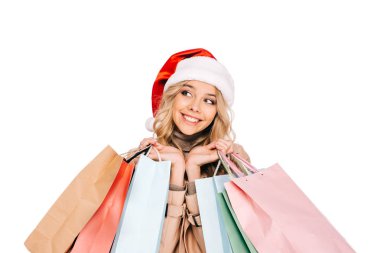 Noel Baba şapkası alışveriş torbaları ve seyir uzağa üzerinde beyaz izole tutan güzel gülümseyen genç kadın