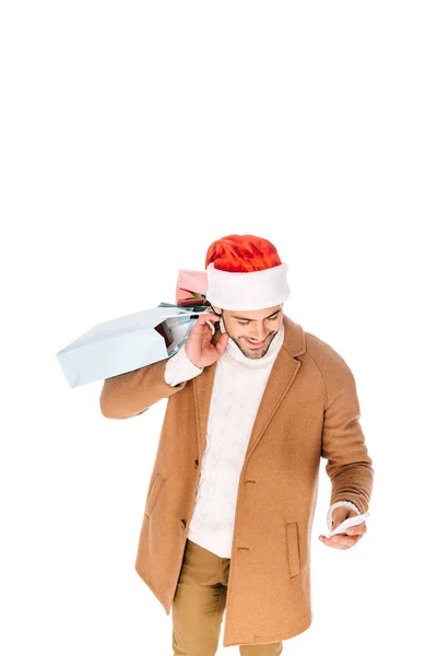 Smiling Young Man Santa Hat Holding Shopping Bags Using Smartphone — Free Stock Photo