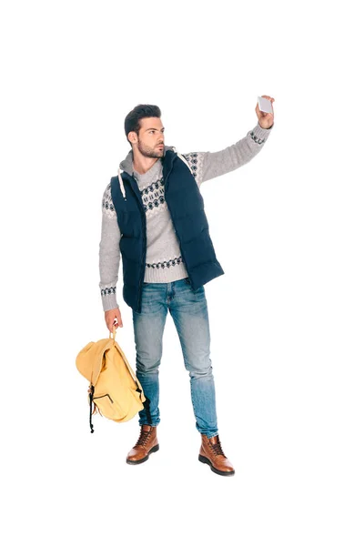 英俊的年轻人手持背包 Amd 采取自拍与智能手机隔离白色 — 免费的图库照片