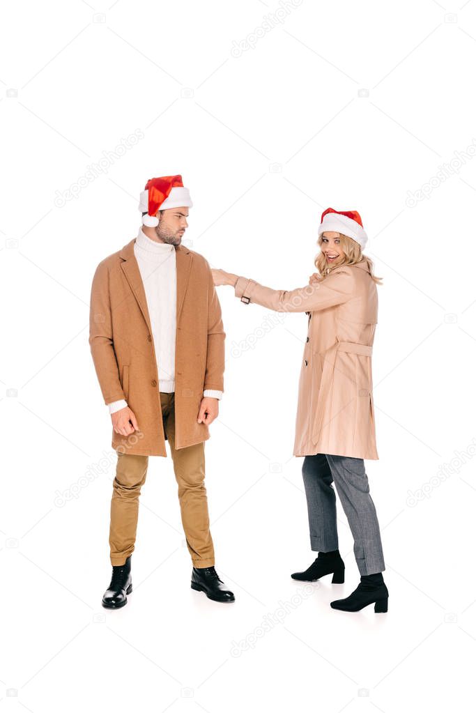 full length view of young couple in santa hats having fun together isolated on white