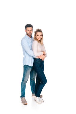 Tam boy görünüm kucaklayan ve üzerinde beyaz izole kamera gülümseyen güzel mutlu genç çift